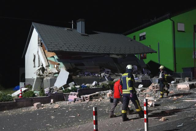 15 July 2026, Rhineland-Palatinate, Rennerod: Firefighters walk past a single-family home in Rennerod, that was severely damaged in an explosion. Two neighbouring buildings also sustained minor damage. Photo: Sascha Ditscher/dpa