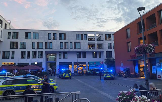 15 July 2026, Hesse, Kelkheim: Police vehicles are parked in the town square in Kelkheim, after a man allegedly killed his wife with a bladed weapon on a public street. Photo: Mike Seeboth/dpa - ACHTUNG: Personen wurden aus rechtlichen Gründen gepixelt.