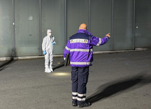15 July 2026, Hesse, Kelkheim: A member of the psychosocial emergency service speaks with a forensic investigator following a fatal attack in Kelkheim. Police said a man fatally attacked his wife with a bladed weapon on a public street before being overpowered by witnesses and arrested. Photo: Mike Seeboth/dpa