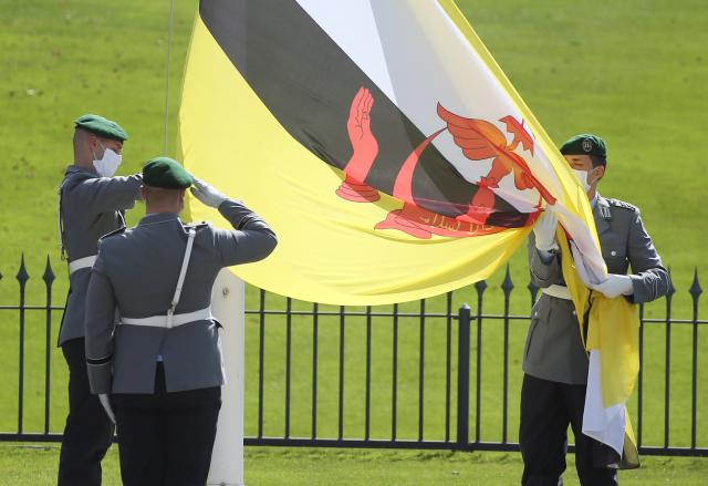 FILED - 20 August 2020, Berlin: FILE PHOTO - Soldiers from the Bundeswehr Guard Battalion raise the flag of Brunei Darussalam in front of Bellevue Palace after the new ambassador presented her credentials to the Federal President. Photo: Wolfgang Kumm/dpa