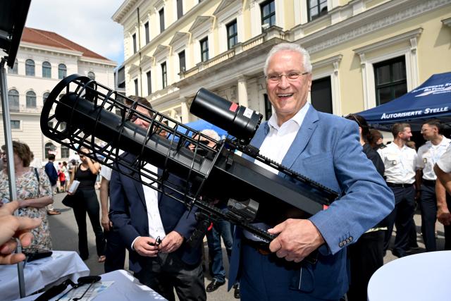 18 July 2026, Bavaria, Munich: Bavarian Interior Minister Joachim Herrmann holds an HP 47 drone defence device (jammer) at a drone defence display on Ludwigstrasse in Munich, Germany, following the official opening of the "80 Years of the Bavarian Police" celebrations. Photo: Felix Hörhager/dpa