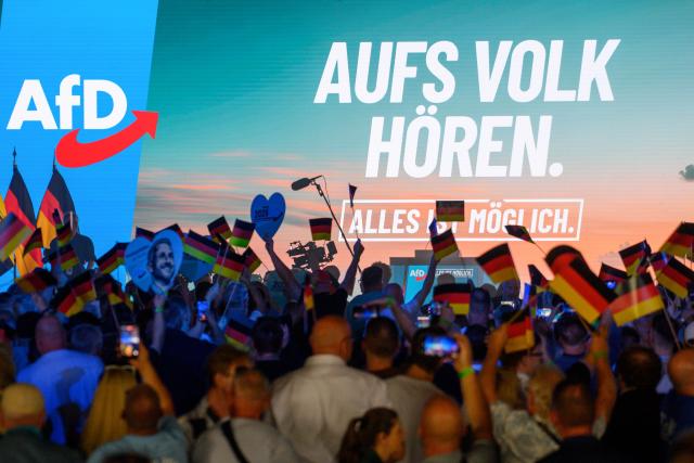 18 July 2026, Saxony-Anhalt, Magdeburg: Participants wave German flags and hold heart-shaped signs bearing the portrait of the AfD's lead candidate as they wait for the start of the AfD Saxony-Anhalt campaign launch in Magdeburg, Germany. The state election in Saxony-Anhalt will be held on 6 September 2026. Photo: Klaus-Dietmar Gabbert/dpa