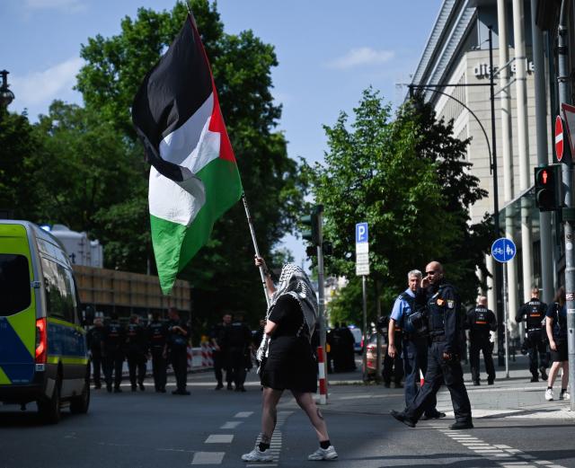18 July 2026, Hesse, Frankfurt am Main: A participant waves a Palestinian flag during a pro-Palestinian demonstration outside the Alte Oper in Frankfurt am Main, Germany. The demonstration is held under the slogan: "Resistance is international law - Palestine has the right to defend itself, even with stones and guns!" Photo: Lea Winkler/dpa