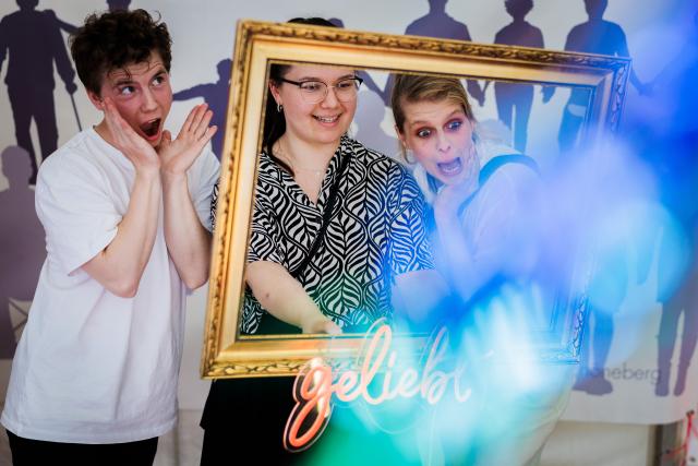 18 July 2026, Berlin: Staff members pose in a picture frame at a photo booth during the Lesbian and Gay City Festival in Berlin's Rainbow Neighbourhood around Nollendorfplatz. Photo: Christoph Soeder/dpa