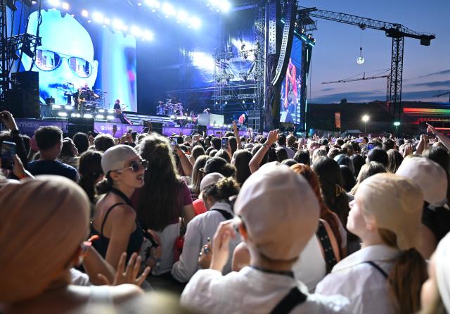 18 July 2026, Berlin: Fans wearing baseball caps dance while American rapper Pitbull performs on stage during the first day of the Lollapalooza Festival at the Berlin Olympic Park. Photo: Elisa Schu/dpa