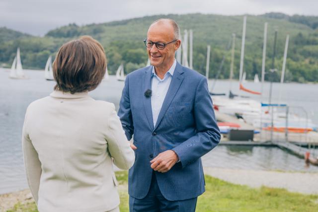 HANDOUT - 19 July 2026, North Rhine-Westphalia, Meschede: This handout provided by ZDF, shows German Chancellor Friedrich Merz being welcomed by Diana Zimmermann, head of the ZDF Berlin studio, to the 2026 ZDF Summer Interview in Meschede. Photo: Dominik Asbach/ZdF/dpa - ATTENTION: editorial use only in connection with the latest coverage and only if the credit mentioned above is referenced in full