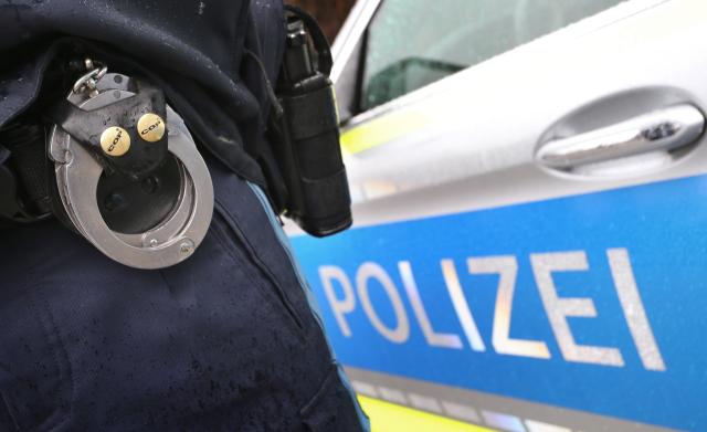 FILED - 15 March 2019, Kempten: FILE PHOTO - A German police officer with handcuffs and a pistol on his belt stands in front of a patrol car. Photo: Karl-Josef Hildenbrand/dpa
