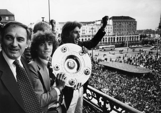 FILED - 08 June 1979, Hamburg: FILE PHOTO -  Hamburg's Kevin Keegan (C) displays the championship trophy alongside coach Branco Zebec (L) and Manfred Kaltz after the German Bundesliga soccer match between Hamburger SV and FC Bayern Munich. Photo: Werner Baum/dpa