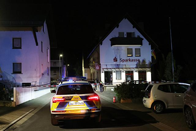 22 July 2026, Bavaria, Waldaschaff: Police stand in front of a savings bank branch in Waldaschaff after an ATM was blown up. Photo: Ralf Hettler/dpa