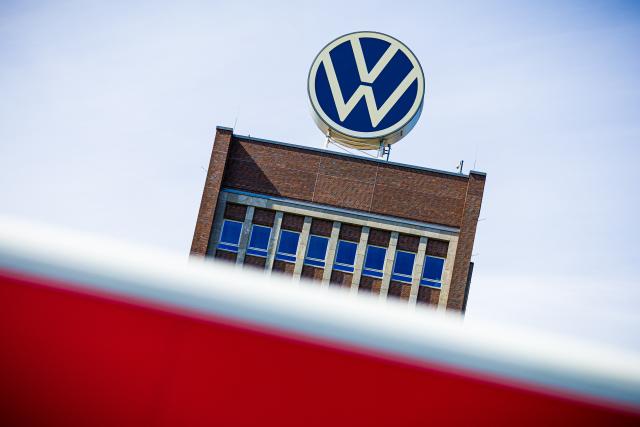 FILED - 04 July 2025, Niedersachsen, Wolfsburg: FILE PHOTO - The Volkswagen logo on the roof of the VW brand skyscraper is seen behind a parked red Transporter. Photo: Moritz Frankenberg/dpa