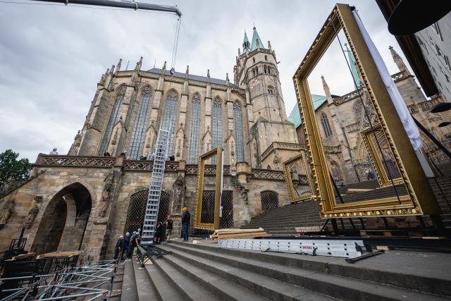 22 July 2026, Thuringia, Erfurt: A high staircase is being hoisted by crane into the set on the cathedral steps for the 2026 DomStufen Festival on Erfurt's Cathedral Square. Starting August 7, 2026, the musical "Jesus Christ Superstar" will be performed on the cathedral steps. Photo: Jacob Schröter/dpa