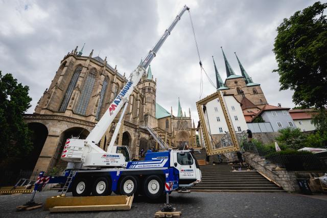 22 July 2026, Thuringia, Erfurt: A high staircase is being hoisted by crane into the set on the cathedral steps for the 2026 DomStufen Festival on Erfurt's Cathedral Square. Starting August 7, 2026, the musical "Jesus Christ Superstar" will be performed on the cathedral steps. Photo: Jacob Schröter/dpa