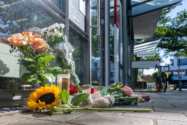 24 July 2026, Bavaria, Regensburg: Flowers and candles have been placed outside the bank branch following the fatal knife attack in Regensburg, Germany. Police continue to investigate the circumstances surrounding the incident. Photo: Armin Weigel/dpa