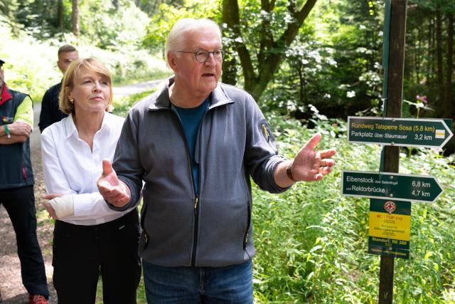 24 July 2026, Sachsen, Eibenstock: German President Frank-Walter Steinmeier speaks alongside his wife, Elke Buedenbender, on a hiking trail along the Sosa Dam. The visit marks the Eibenstock Charcoal-Burning Experience. Photo: Sebastian Kahnert/dpa