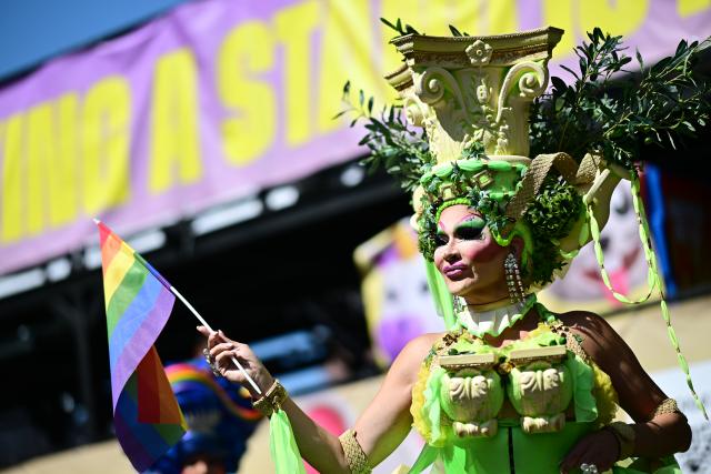 25 July 2026, Berlin: A person in costume holds a rainbow flag during a demonstration under the slogan "Taking a Stand Is Hot" at Christopher Street Day (CSD) in Berlin. For the first time, Berlin's CSD is taking place over two days. Photo: Fabian Sommer/dpa
