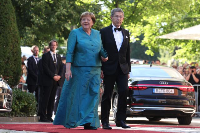 25 July 2026, Bavaria, Bayreuth: Former German Chancellor Angela Merkel (R) and her husband Joachim Sauer arrive at the Festspielhaus for the opening of the Richard Wagner Festival. The Bayreuth Festival kicks off its 150th anniversary with Ludwig van Beethoven's Ninth Symphony. Photo: Karl-Josef Hildenbrand/dpa
