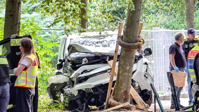 26 July 2026, Berlin, berlin: A wrecked white vehicle is parked in the Tiergarten area, where it had crashed into a tree. On the sidelines of Christopher Street Day in Berlin, the vehicle had plowed into a crowd. One woman was killed and 16 other people were injured, some seriously. Photo: Jason Tschepljakow/dpa