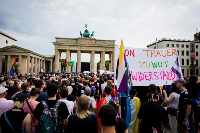 26 July 2026, Berlin: People hold a banner that reads, "From Grief to Anger to Resistance!" during a demonstration in front of the Brandenburg Gate. Christopher Street Day in Berlin had been cut short the day before after a car plowed into a crowd on the outskirts of the large-scale event. Photo: Christoph Soeder/dpa