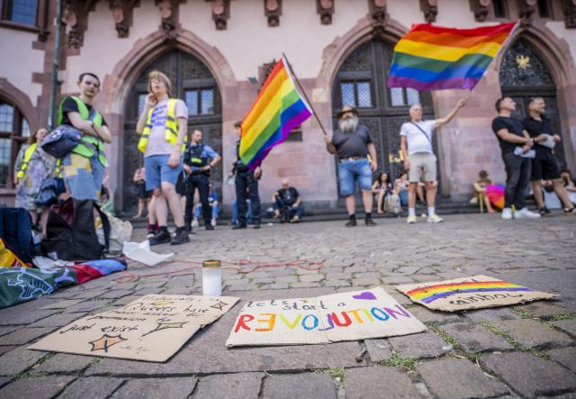 26 July 2026, Hesse, Frankfurt: People gather with flags during a vigil on the Roemerberg following the attack on the outskirts of the Christopher Street Day (CSD) in Berlin is being held on the Römer in Frankfurt. Fridays for Future and CSD Frankfurt have called for this event. Photo: Andreas Arnold/dpa