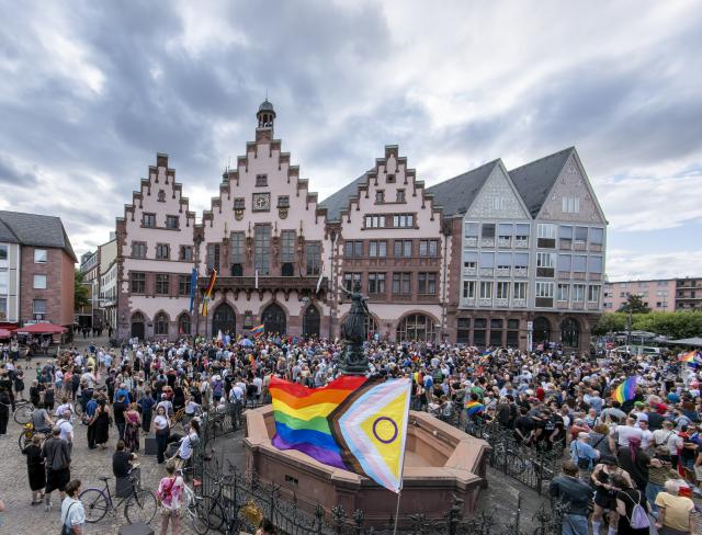 26 July 2026, Hesse, Frankfurt: People gather with flags during a vigil on the Roemerberg following the attack on the outskirts of the Christopher Street Day (CSD) in Berlin is being held on the Römer in Frankfurt. Fridays for Future and CSD Frankfurt have called for this event. Photo: Andreas Arnold/dpa