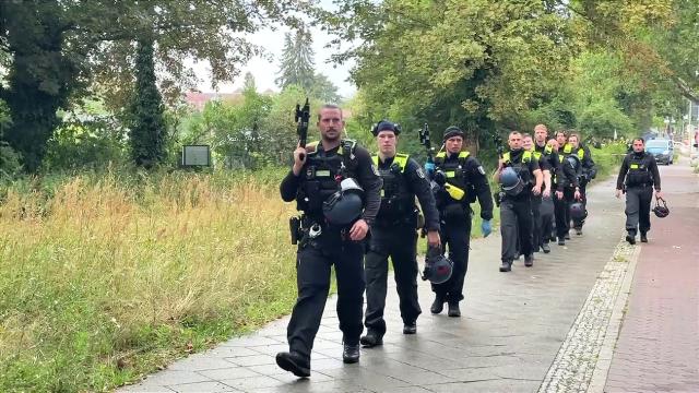 26 July 2026, Berlin: Police officers walk on the scene at an allotment garden community in Berlin-Spandau. According to information from security sources, one person was killed during a police operation in Spandau following the terrorist attack on the sidelines of Christopher Street Day (CSD). Photo: Michael Kappeler/dpa