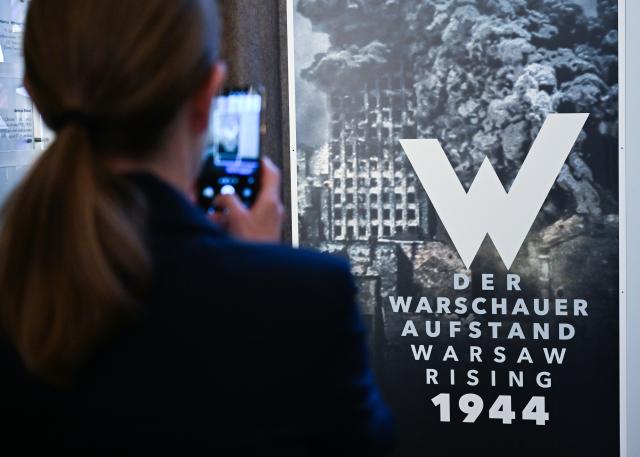 27 July 2026, Berlin: A woman takes a photo with her smartphone at the Rotes Rathaus during the opening of the exhibition "The Warsaw Uprising of 1944." Photo: Soeren Stache/dpa
