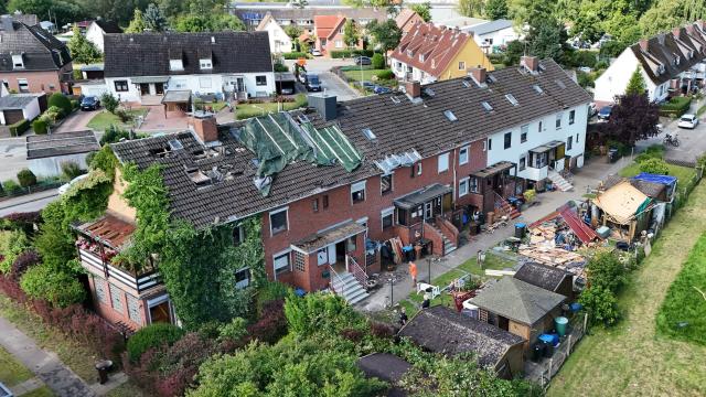 27 July 2026, Schleswig-Holstein, Glückstadt: An aerial drone view shows temporary tarps covering the roof of a damaged townhouse in Glueckstadt. A suspected tornado left a trail of destruction across the region, destroying roofs and power lines, with initial police estimates putting the total damage at a six- to seven-figure sum Photo: Marcus Brandt/dpa