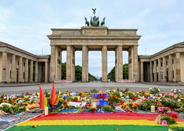 27 July 2026, Berlin: Flowers, candles, messages, and a rainbow flag can be seen on Pariser Platz in front of the Brandenburg Gate, following the terrorist attack on the sidelines of Christopher Street Day (CSD) after a car plowed into a crowd. Photo: Soeren Stache/dpa