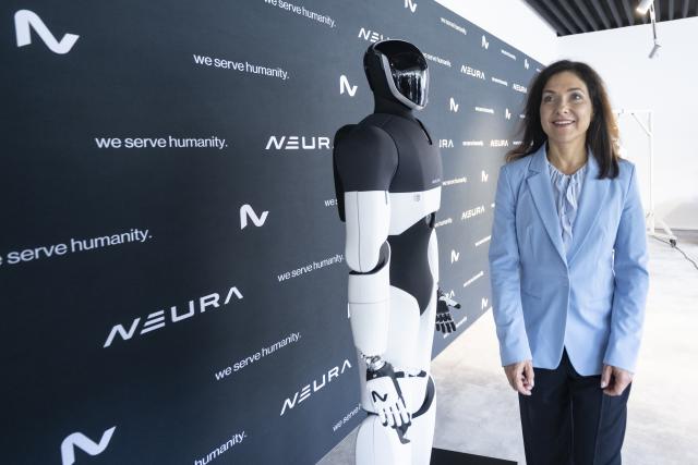 27 July 2026, Baden-Wuerttemberg, Metzingen: German Minister of Economic Affairs Katherina Reiche walks alongside a robot during a visit to the robotics startup Neura Robotics. Photo: Marijan Murat/dpa