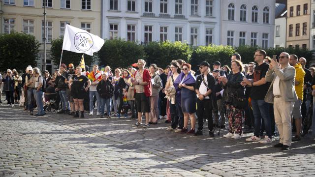 27 July 2026, Mecklenburg-Western Pomerania, Schwerin: People attend a vigil at Schwerin's market square. Following the suspected Islamist terrorist attack on the sidelines of Christopher Street Day (CSD) in Berlin, the Schwerin CSD Association has called for a vigil in Mecklenburg-Western Pomerania's state capital. Photo: Philip Dulian/dpa
