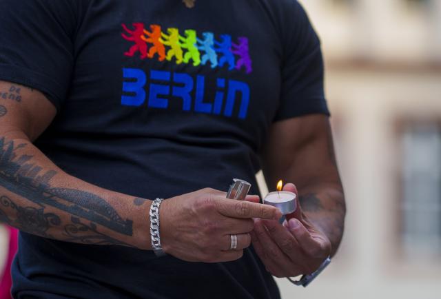 27 July 2026, Hesse, Frankfurt_Main: A man wearing a T-shirt featuring the Berlin Bear in rainbow colors lights a candle at the memorial rally on Paulsplatz, following the attack on the outskirts of the Christopher Street Day (CSD) in Berlin. Photo: Andreas Arnold/dpa