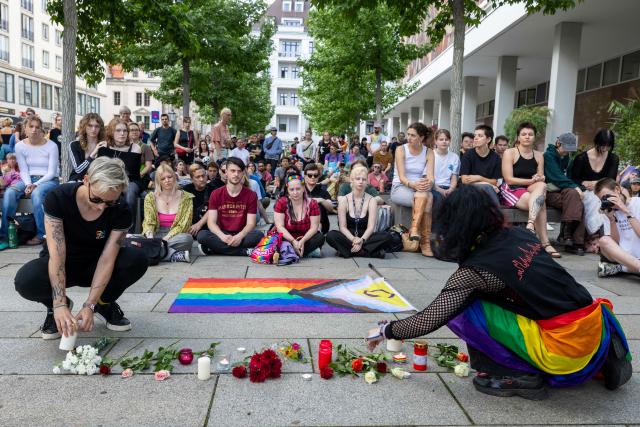 27 July 2026, Saxony, Dresden: Flowers and lit candles are placed on the ground in front of a rainbow flag at the vigil held by Queer Pride Dresden and other groups in response to the terrorist attack on the sidelines of Christopher Street Day (CSD) in Berlin. Photo: Daniel Wagner/dpa