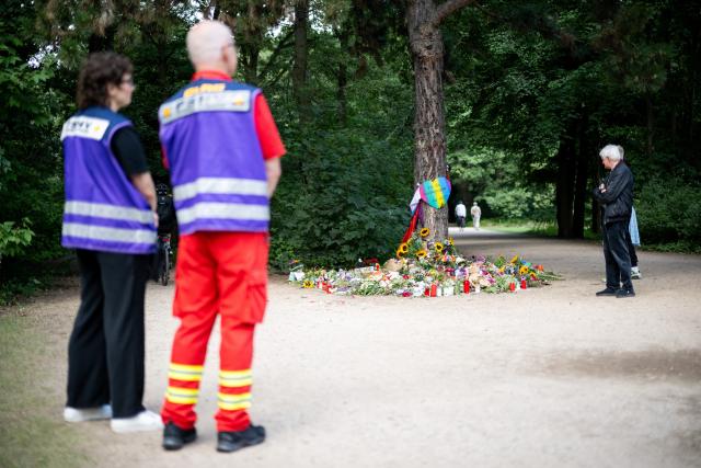 28 July 2026, Berlin: Members of a crisis intervention team and mourners gather next to a memorial site in the Tiergarten park in Berlin. A man drove a vehicle into a crowd of people on the sidelines of the Christopher Street Day (CSD) parade, leaving several injured. Photo: Sebastian Christoph Gollnow/dpa