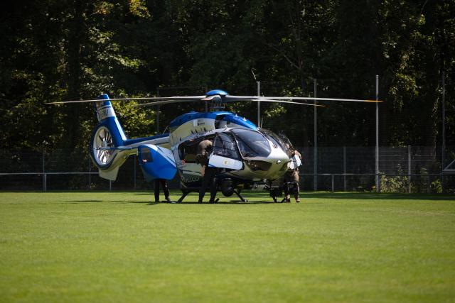 29 July 2026, Baden-Württemberg, Weil am Rhein: Police officers stand next to a police helicopter that had previously landed on a soccer field. During a major operation in Weil am Rhein, police special forces arrested a man wanted on an arrest warrant. To avoid jeopardizing the ongoing investigation, a police spokesperson declined to provide further details. Photo: Jose Villacreses/dpa