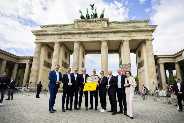 29 July 2026, Berlin: (L-R) Minister-President of Saxony-Anhalt Sven Schulze, Minister-President of Saxony Michael Kretschmer, Minister-President of Thuringia Mario Voigt, President of the German Cycling Federation Bernd Dankowski, Director of the Tour de France Christian Prudhomme, Managing Director of ASO Germany Yann Le Moenner, Governing Mayor of Berlin Kai Wegner, Rudolf Scharping and Minister of State and Federal Government Commissioner for Eastern Germany Elisabeth Kaiser stand in front of the Brandenburg Gate during a photo of marking the handover of the bid to host the start of the 2029 Tour de France in Central Germany to Tour Director Prudhomme. Photo: Christoph Soeder/dpa