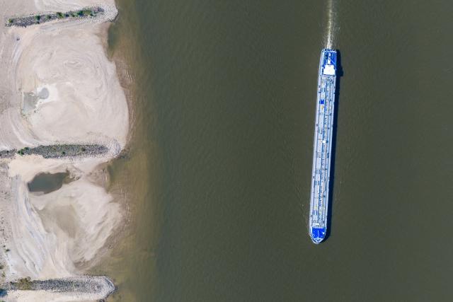 30 July 2026, North Rhine-Westphalia, Duisburg: A ship sails in the channel on the Rhine in Duisburg, amid low water levels that have exposed wide sandbars, normally submerged, along the shore. Photo: Christoph Reichwein/dpa