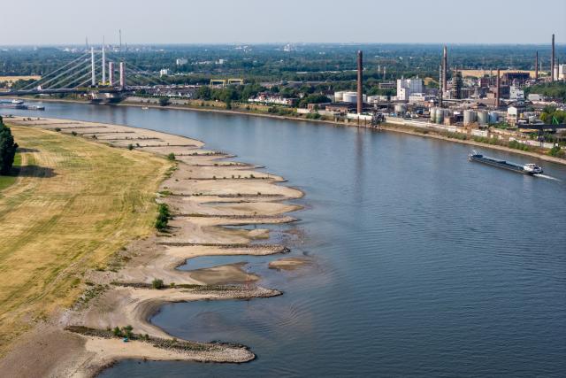 30 July 2026, North Rhine-Westphalia, Duisburg: A ship sails in the channel on the Rhine in Duisburg, amid low water levels that have exposed wide sandbars, normally submerged, along the shore. Photo: Christoph Reichwein/dpa