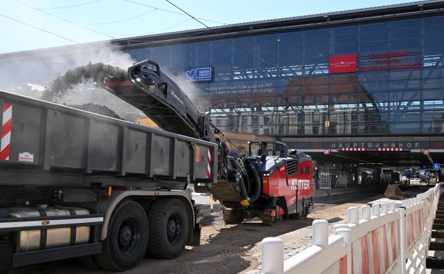 30 July 2026, Thuringia, Erfurt: A specialized construction vehicle transfers a black material into the bed of a waiting transport truck at the work site to replace the tram tracks at the main train station. During the Thuringian summer break, Erfurter Verkehrsbetriebe (Evag) is replacing the tracks at Stadtparkkopf and in the station underpass leading to Willy-Brandt-Platz. Photo: Martin Schutt/dpa