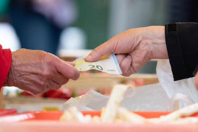 FILED - 15 May 2026, Saxony, Dresden: FILE PHOTO - A woman pays for her groceries with cash at a weekly market. Photo: Sebastian Kahnert/dpa