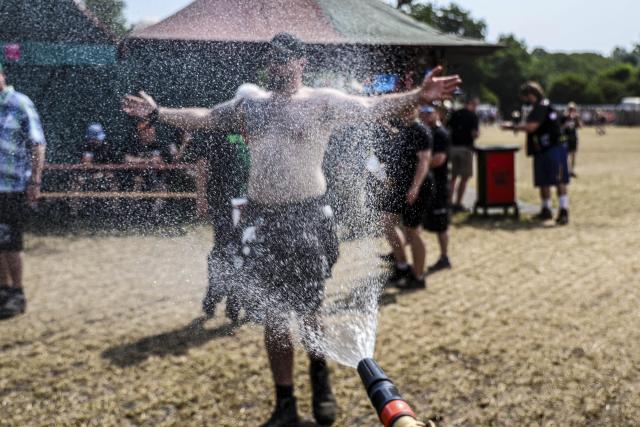 30 July 2026, Schleswig-Holstein, Wacken: A man cools off in front of a garden hose at the Wacken Open Air (W:O:A) festival. W:O:A is considered the world's largest heavy metal festival. Photo: Frank Molter/dpa