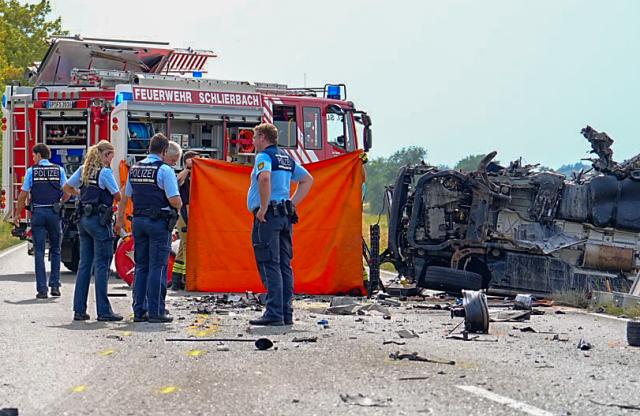 31 July 2026, Baden-Wuerttemberg, Kirchheim: Police officers and other emergency responders stand on the road next to the wreckage of the small van following a serious accident-a head-on collision between a bus and a small van on the B297 near Kirchheim and Schlierbach Photo: Enrique Kaczor/dpa