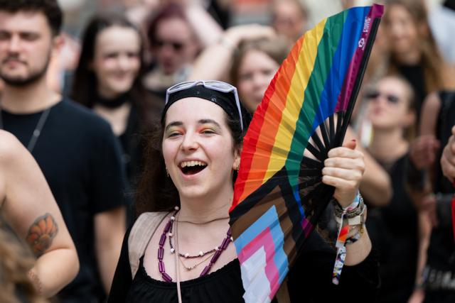 01 August 2026, Hesse, Schluechtern: A participant walks in the Christopher Street Day (CSD) parade carrying a rainbow-colored fan. Photo: Florian Wiegand/dpa