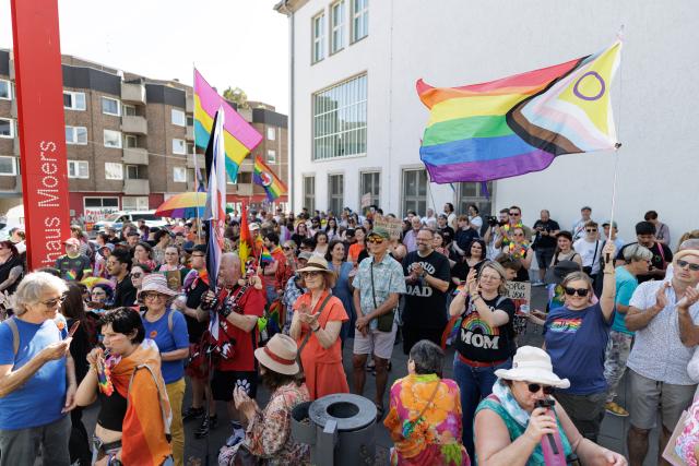 01 August 2026, North Rhine-Westphalia, Moers: People take part in the Christopher Street Day (CSD) Pride Parade rally in front of City Hall. Photo: David Ebener/dpa