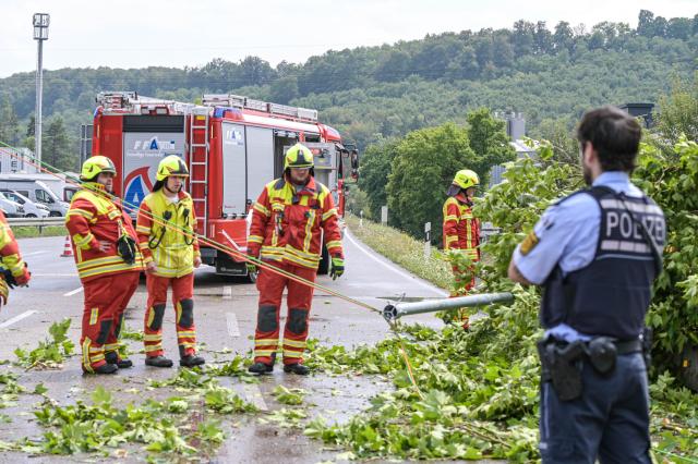 01 August 2026, Baden-Wuerttemberg, Amstetten: Firefighters and police stand on the scene dealing with a fallen traffic light. The traffic light was knocked down by falling trees following a brief but intense thunderstorm. Photo: -/onw-images/dpa