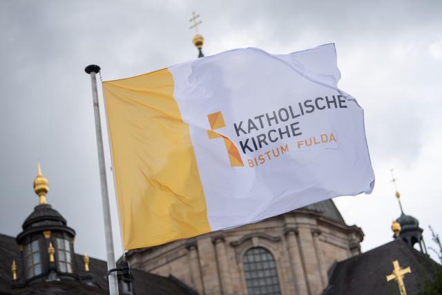 FILED - 26 September 2022, Hesse, Fulda: FILE PHOTO - A flag bearing the inscription "Catholic Church, Diocese of Fulda" flies in front of St. Salvator Cathedral in Fulda during the fall plenary assembly of the German Bishops' Conference. Photo: Sebastian Gollnow/dpa