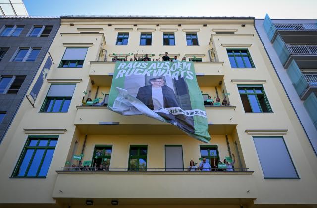 03 August 2026, Berlin: Staff members unfurl a banner on the facade of the federal headquarters of Alliance 90/The Greens ahead of the Berlin House of Representatives election. The banner features the party's lead candidate, Werner Graf, and the slogan 'Get Out of the Past'. Photo: Soeren Stache/dpa