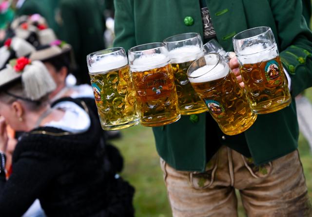 FILED - 04 June 2026, Bavaria, Wackersberg: A man carries beer mugs through the beer garden after a Corpus Christi procession. Photo: Sven Hoppe/dpa