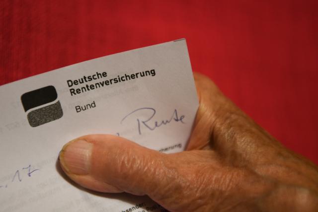 FILED - 07 November 2017, Weingarten: File Photo - A pensioner holds her pension certificate in her hand. Photo: Felix Kästle/dpa