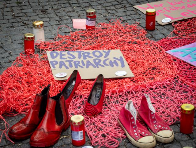 05 August 2026, Berlin: During a rally against femicide, pairs of red shoes are displayed in front of Schöneberg City Hall next to a cardboard sign reading "Destroy Patriarchy." Red shoes are recognized worldwide as a symbol of violence against women. Photo: Soeren Stache/dpa