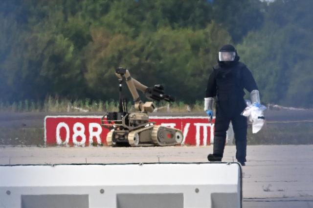 05 August 2026, Saxony, Schkeuditz: A forensic technician is working alongside a bomb-disposal robot near a Ukrainian aircraft at Leipzig/Halle Airport. Specialists from the Federal Police defused a drone equipped with an explosive device at the airport. Photo: Hendrik Schmidt/dpa